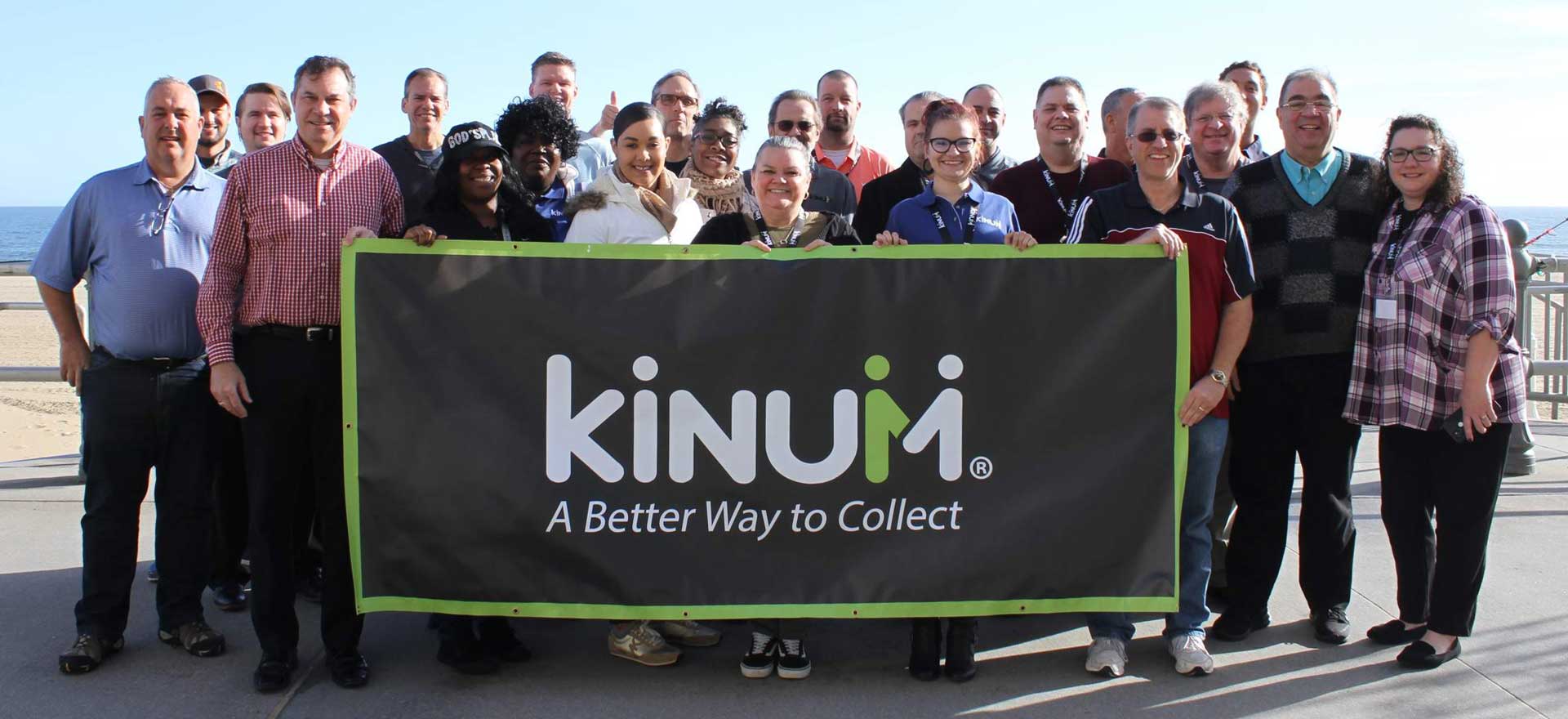 Kinum team holding a company banner at the beach