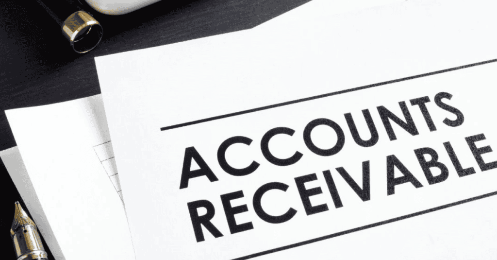 A paper with the bold heading Accounts Receivable lies on a desk beside a fountain pen and other documents.