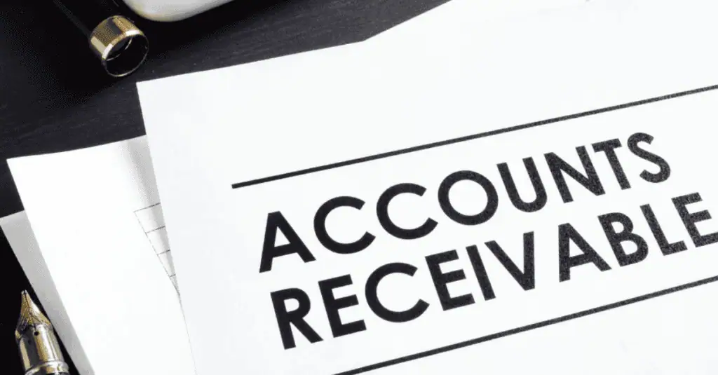A paper with the bold heading Accounts Receivable lies on a desk beside a fountain pen and other documents.