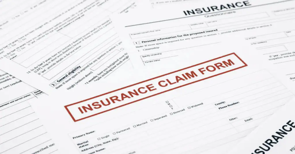 Several insurance forms are spread out on a surface, with a prominent Insurance Claim Form in the center, featuring bold red text.