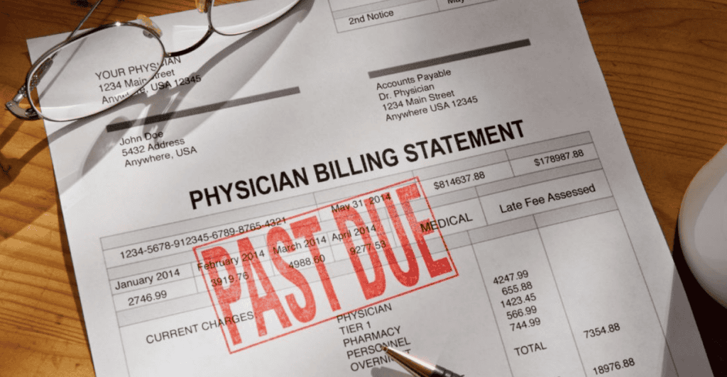 A physician billing statement with a large red PAST DUE stamp across it lies on a wooden desk, next to a pair of glasses and a pen.